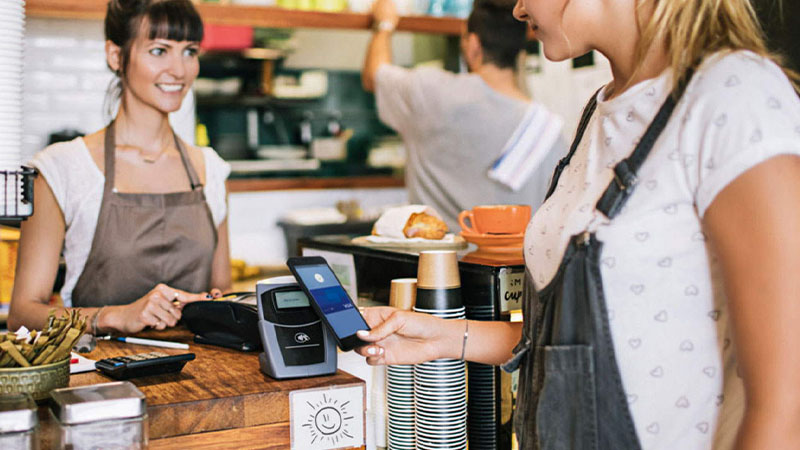 women in coffee shop paying contactless