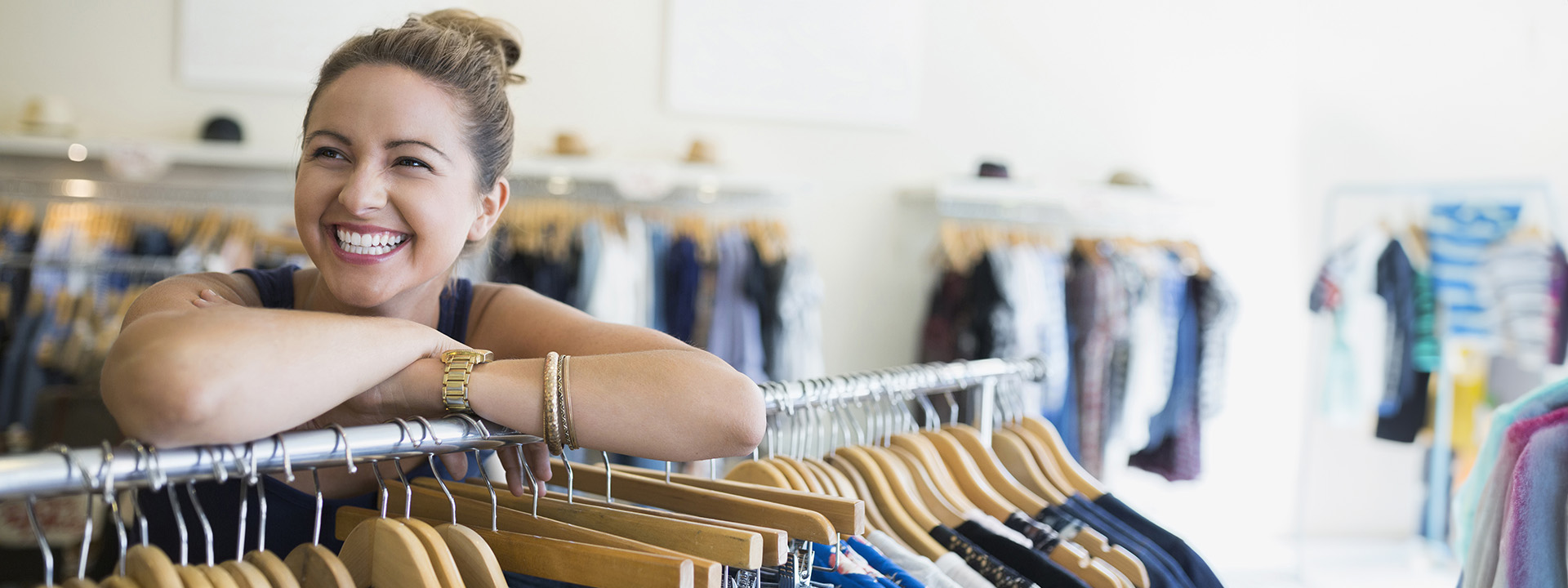 woman smiling leaning on clothing rail