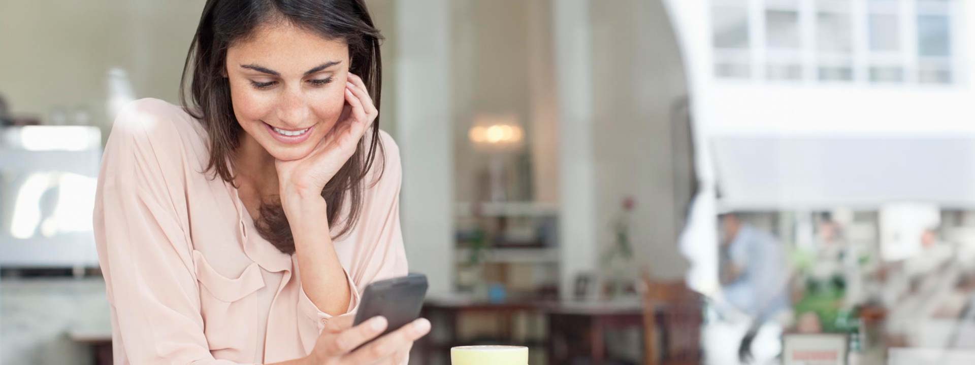 woman smiling with hand on face using mobile phone