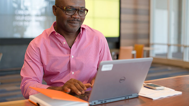 man sitting at desk in office with laptop