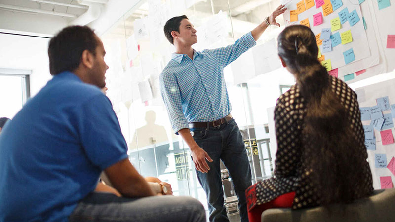 man pointing to board in meeting